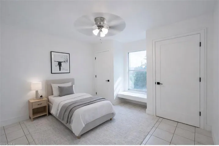 Staged - Guess bedroom featuring light tile patterned floors, a ceiling fan, and two closets