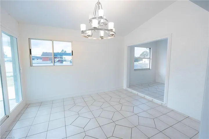 Unfurnished dining area with lofted ceiling, a chandelier, and light tile patterned floors