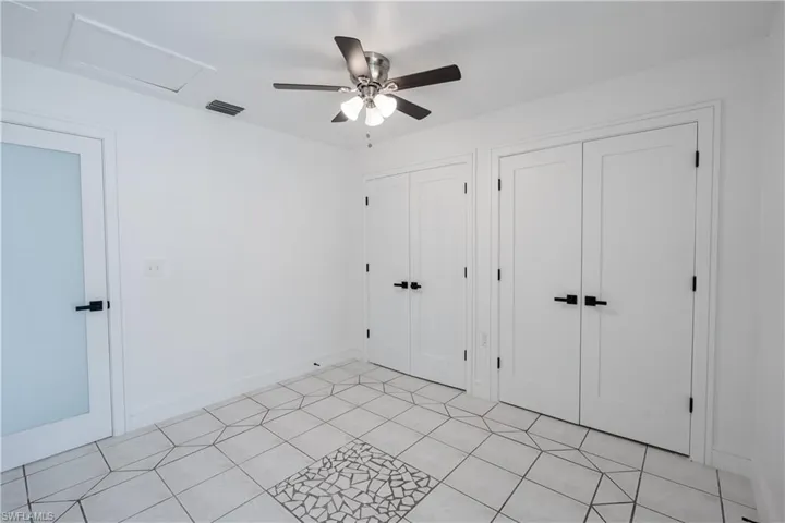 Unfurnished guess bedroom featuring two closets and ceiling fan