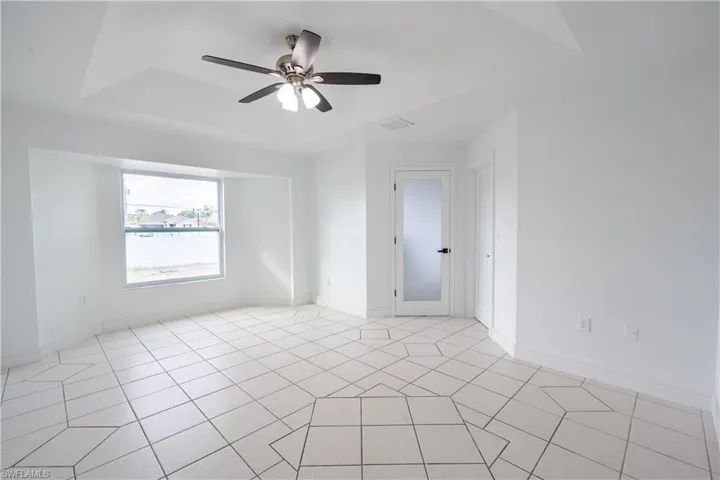 Unfurnished room featuring ceiling fan and a tray ceiling