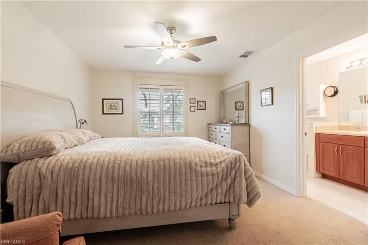 Carpeted bedroom with ceiling fan, connected bathroom, and sink