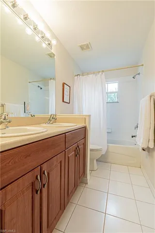Full bathroom featuring toilet, shower / tub combo, tile patterned flooring, and vanity