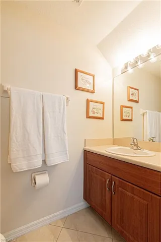 Bathroom with tile patterned flooring, vaulted ceiling, toilet, vanity, and a textured ceiling