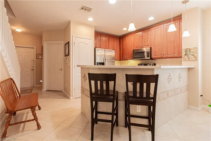 Kitchen featuring kitchen peninsula, stainless steel appliances, light tile patterned floors, and a breakfast bar area