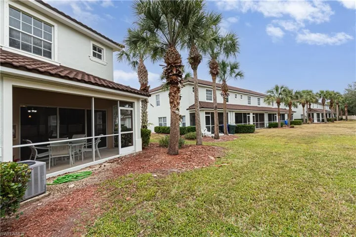 Back of property with central air condition unit, a yard, and a sunroom