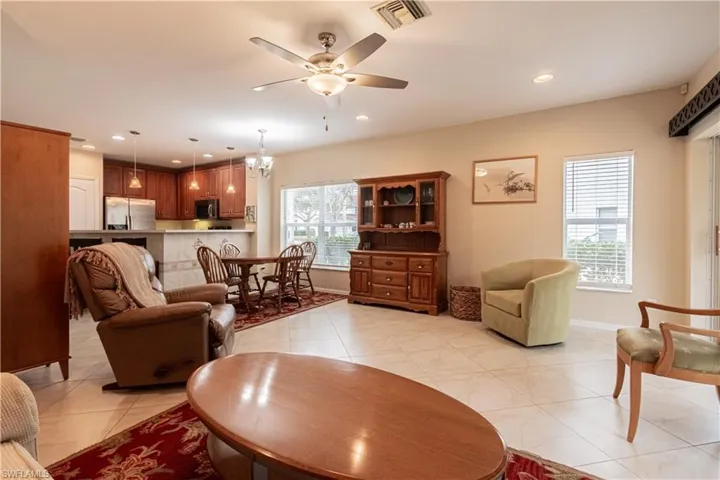 Living room with ceiling fan with notable chandelier and light tile patterned flooring
