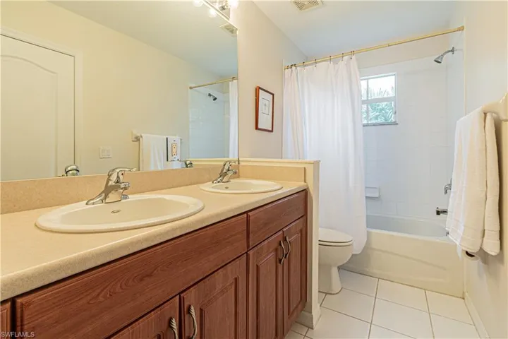 Full bathroom featuring toilet, vanity, tile patterned floors, and shower / bath combo with shower curtain