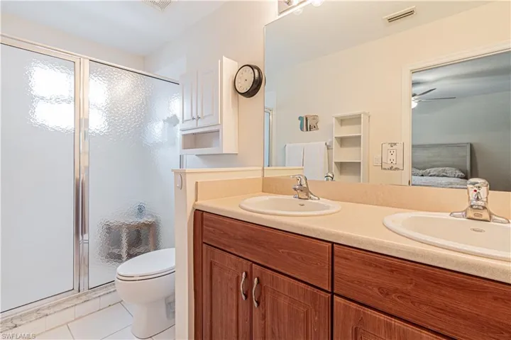 Bathroom featuring ceiling fan, toilet, walk in shower, tile patterned floors, and vanity