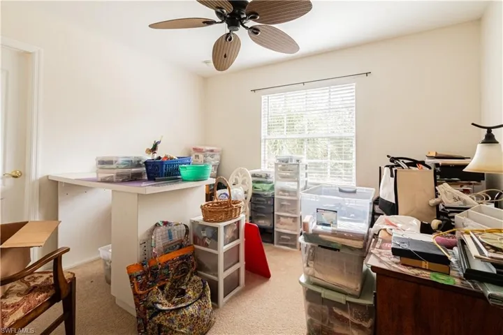 Carpeted home office featuring ceiling fan