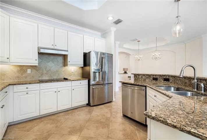 Kitchen featuring sink, decorative light fixtures, stainless steel appliances, and white cabinets