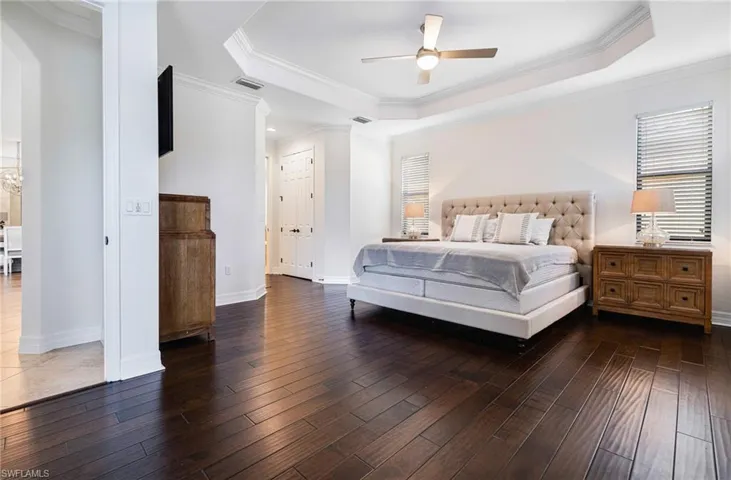 Bedroom featuring ceiling fan, a raised ceiling, crown molding, and dark hardwood / wood-style floors