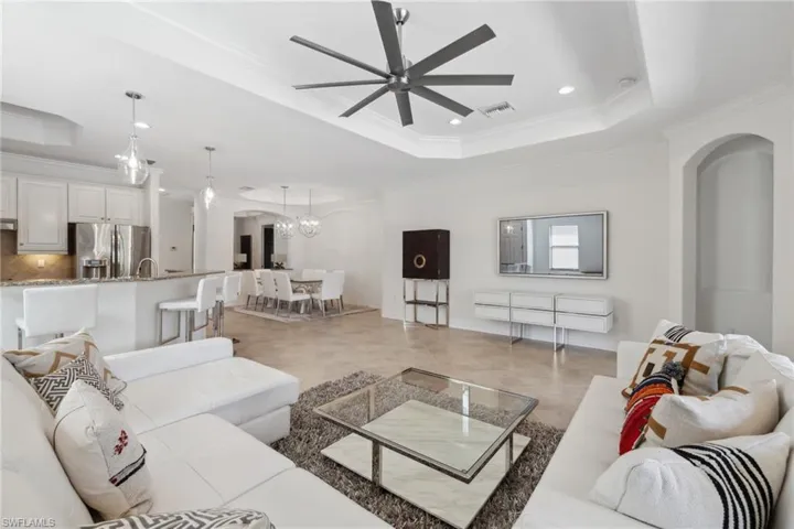 Living room with crown molding, ceiling fan, and a tray ceiling