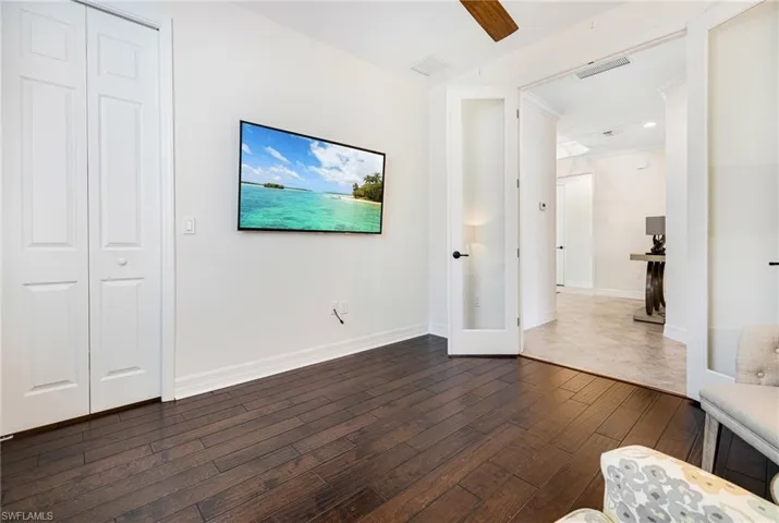 Unfurnished living room featuring ornamental molding, dark wood-type flooring, and ceiling fan
