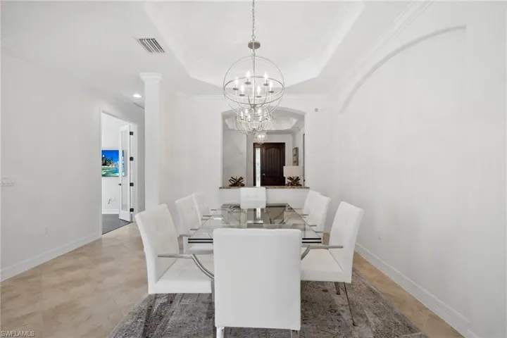 Dining space featuring ornamental molding, a tray ceiling, and a notable chandelier