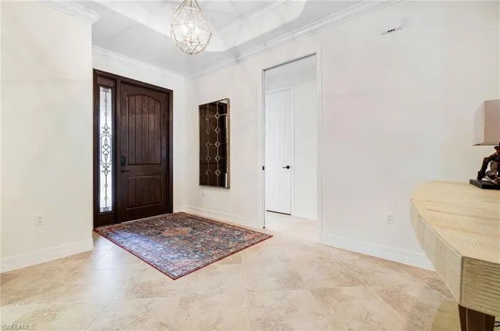 Entrance foyer with a notable chandelier, a wealth of natural light, and crown molding