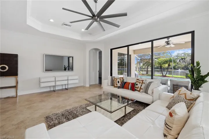 Living room with crown molding, ceiling fan, and a tray ceiling