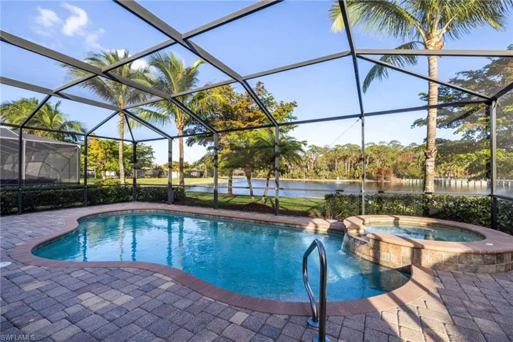 View of pool featuring a patio, an in ground hot tub, a water view, and a lanai