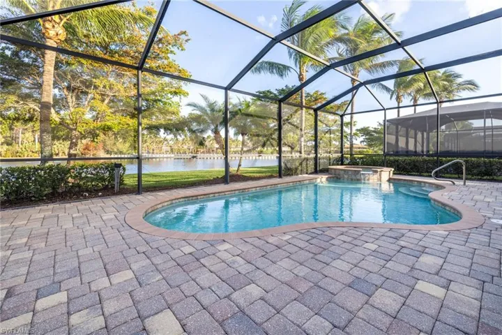 View of pool featuring a water view, an in ground hot tub, glass enclosure, and a patio area