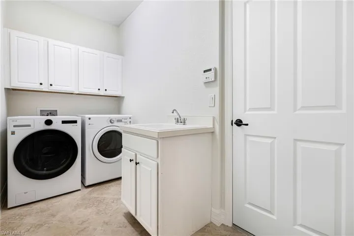 Washroom with sink, independent washer and dryer, and cabinets