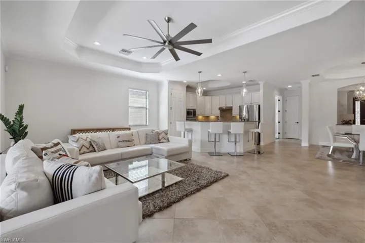 Living room with crown molding, a raised ceiling, and ceiling fan