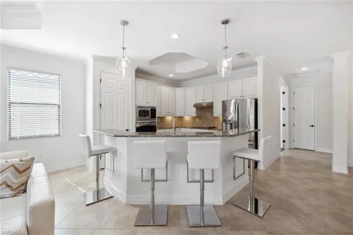 Kitchen featuring hanging light fixtures, white cabinetry, appliances with stainless steel finishes, and dark stone countertops