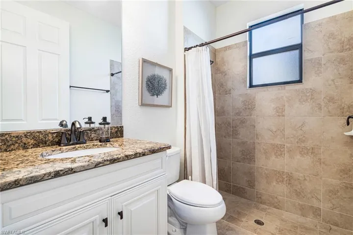 Bathroom featuring vanity, curtained shower, and toilet