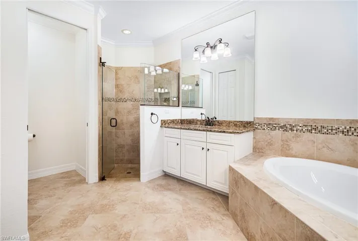 Bathroom featuring vanity, ornamental molding, and separate shower and tub