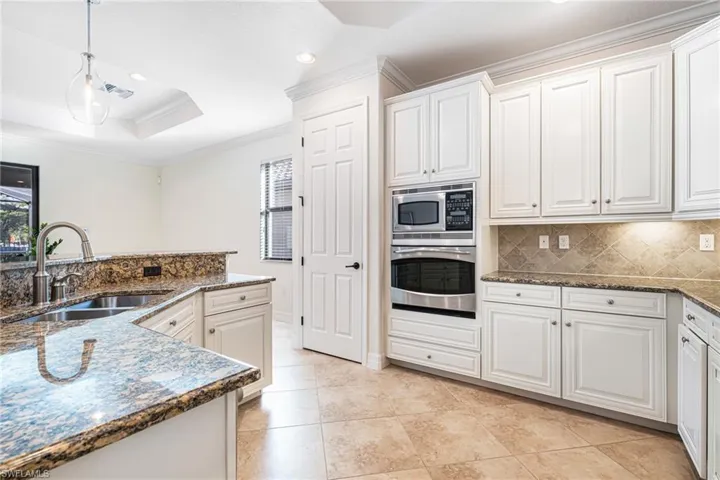 Kitchen featuring white cabinetry, stainless steel appliances, a raised ceiling, and sink