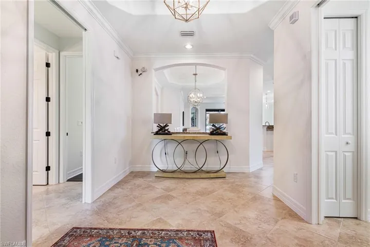 Hallway with ornamental molding and a chandelier