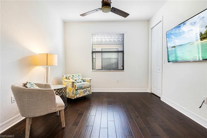 Living area with ceiling fan, dark wood-type flooring, and a wealth of natural light