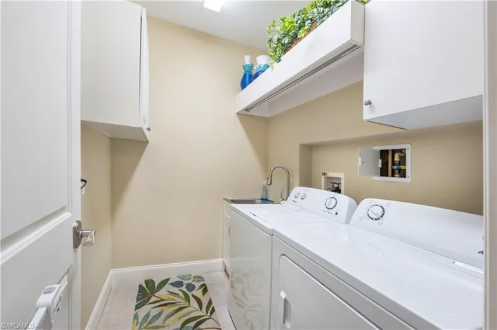 Laundry area with cabinets, washer and dryer, and light tile patterned flooring