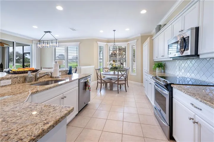 Kitchen with stainless steel appliances, hanging light fixtures, sink, and white cabinets