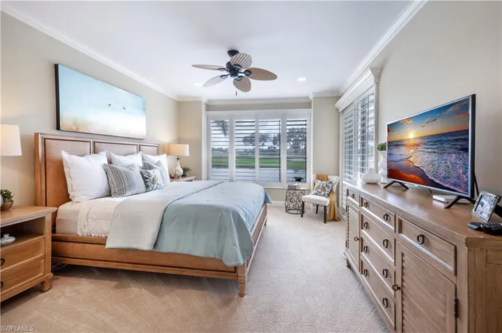 Bedroom featuring light carpet, ornamental molding, and ceiling fan