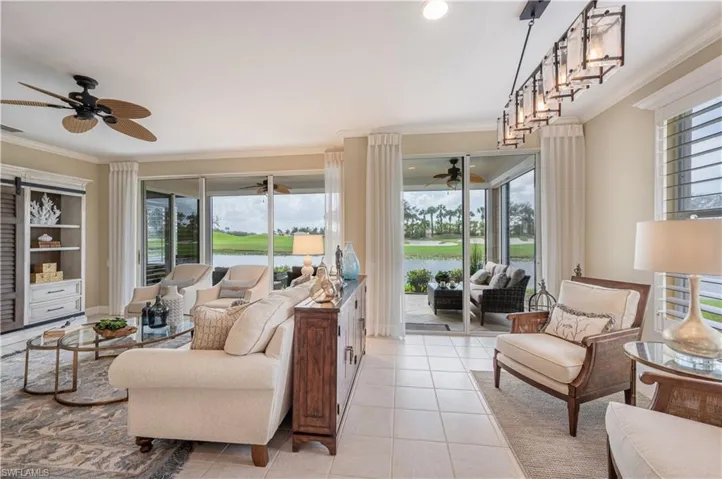 Living room featuring crown molding, ceiling fan, a water view, and light tile patterned floors