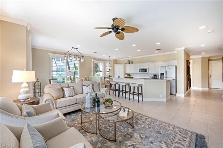 Living room featuring ornamental molding, ceiling fan, and light tile patterned floors