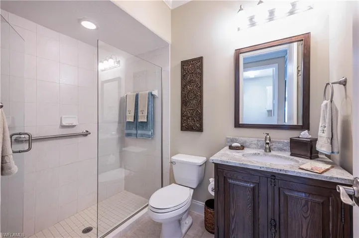 Bathroom featuring toilet, tile patterned flooring, vanity, and a shower with door