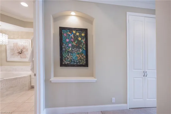 Corridor featuring crown molding, light tile patterned flooring, and an inviting chandelier