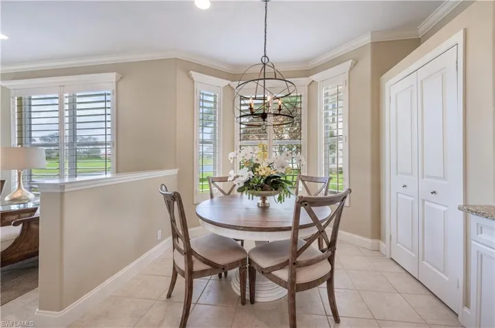 Tiled dining space with a notable chandelier, ornamental molding, and a wealth of natural light