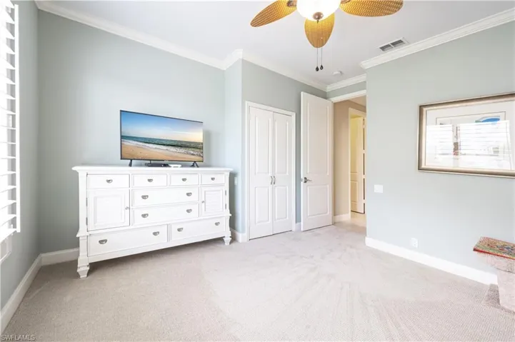 Unfurnished bedroom featuring ceiling fan, light carpet, and ornamental molding