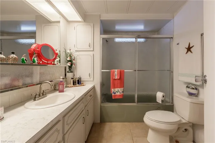 Full bathroom with enclosed tub / shower combo, toilet, ornamental molding, vanity, and tile patterned flooring