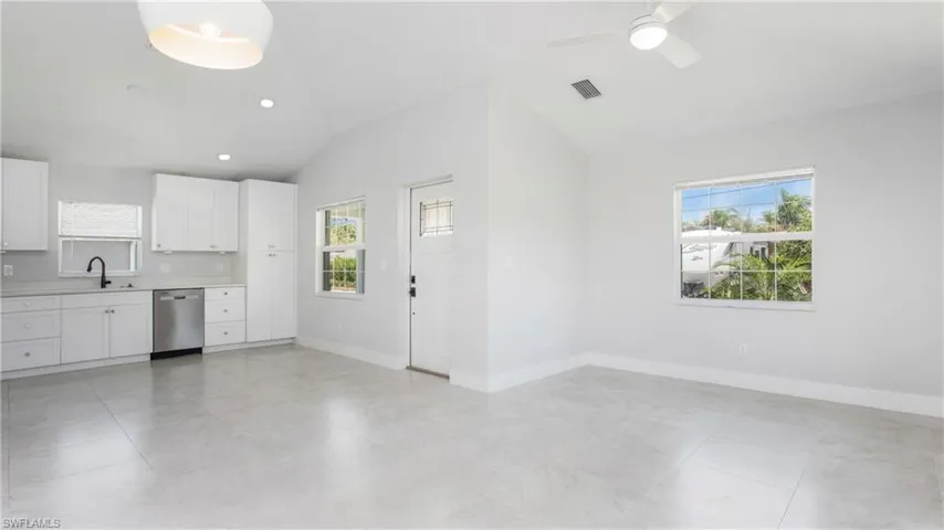 Kitchen with stainless steel dishwasher, lofted ceiling, healthy amount of natural light, light countertops, and ceiling fan