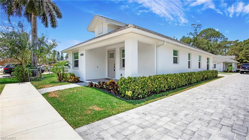 View of property exterior featuring stucco siding, a yard, and decorative driveway