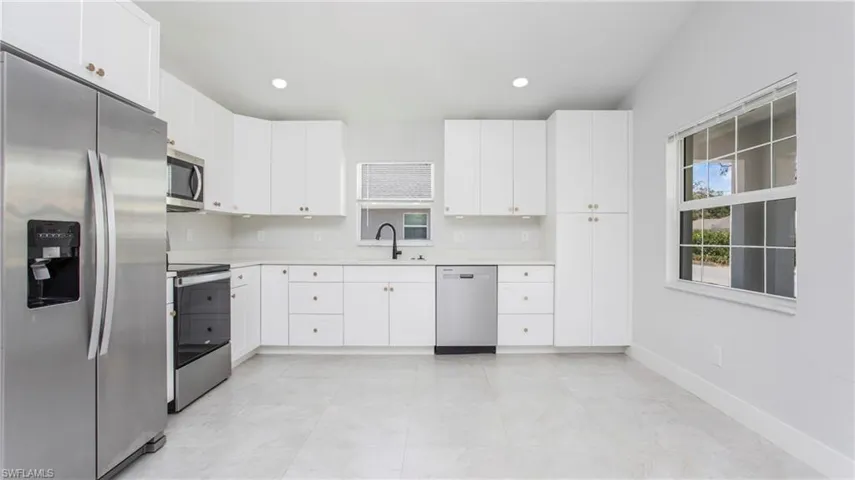 Kitchen featuring stainless steel appliances, a sink, light countertops, white cabinetry, and recessed lighting