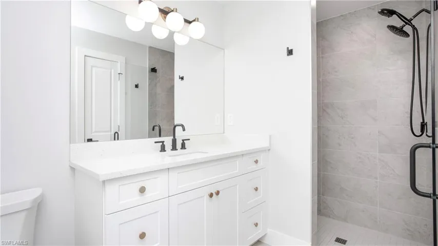 Full bath featuring a shower stall, vanity, and toilet