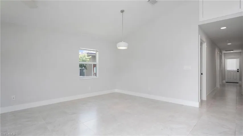 Empty room featuring plenty of natural light, baseboards, and lofted ceiling