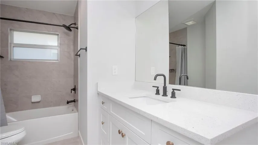 Full bath featuring toilet, vanity, and shower / tub combo