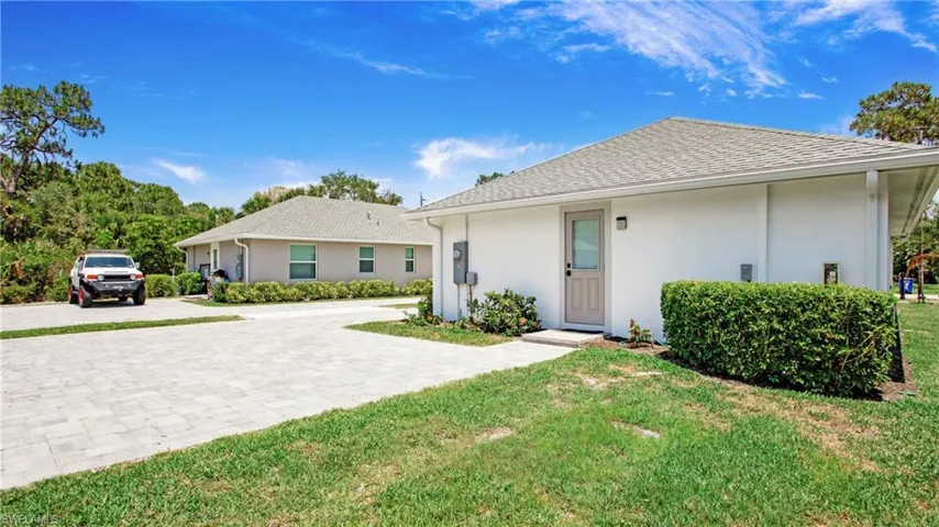 View of front of home featuring decorative driveway, stucco siding, a front lawn, and roof with shingles