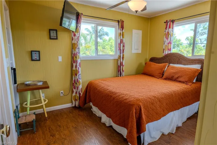 Bedroom with wood finished floors, ornamental molding, a ceiling fan, and electric panel