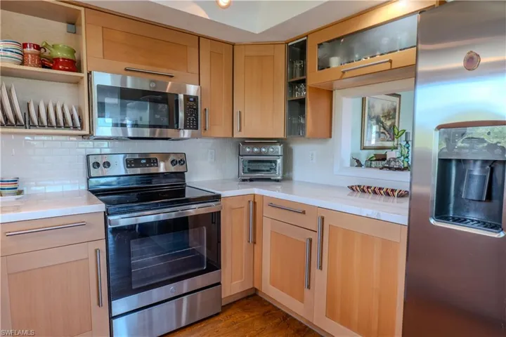 Kitchen featuring stainless steel appliances, light brown cabinetry, light countertops, and backsplash