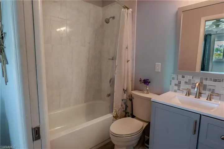 Full bath featuring shower / bath combo, decorative backsplash, and vanity